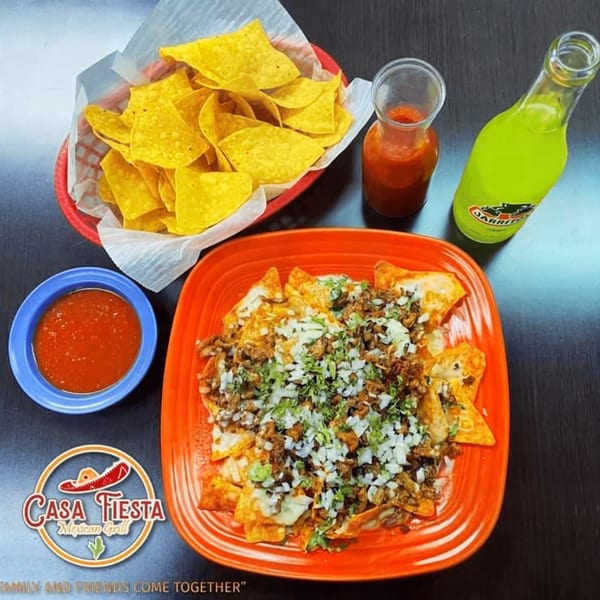 Casa Fiesta Mexican Grill nachos with meat, cheese, onions, cilantro, chips, salsa, and Jarritos.