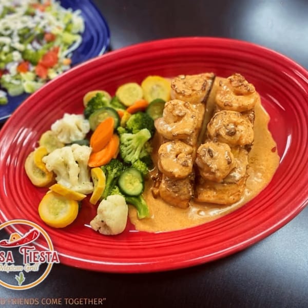 Casa Fiesta Mexican Grill's shrimp dish with vegetables on a red plate, and a salad in the background.