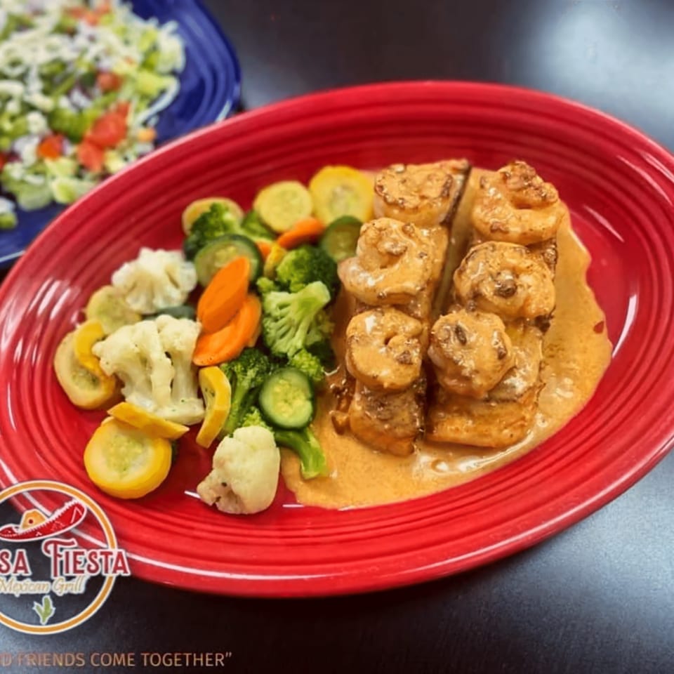 Casa Fiesta Mexican Grill's shrimp dish with vegetables on a red plate, and a salad in the background.