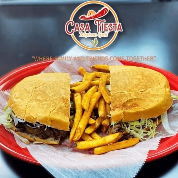 A Casa Fiesta Mexican Grill torta sandwich, cut in half, with a side of golden french fries.