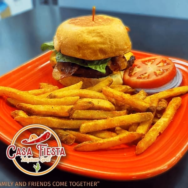 A Casa Fiesta burger with cheese, lettuce, and bacon, served with fries and a tomato slice.